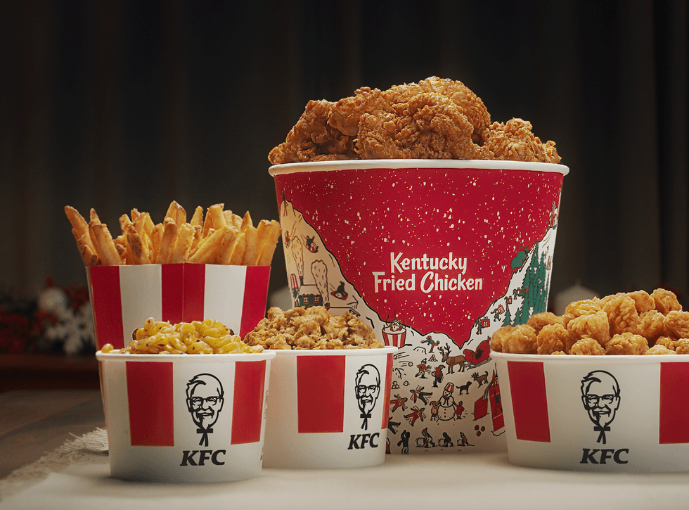 KFC combo with a buckets of chicken, fries, stuffing and sides.