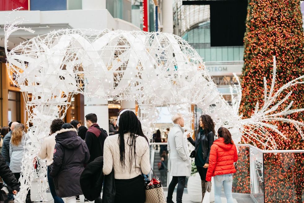 A group of visitors mingle in front of the large illuminated reindeer decoration at CF Toronto Eaton Centre.