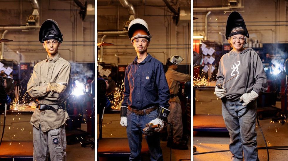 Three welding students, each one wearing workwear, gloves and welding masks and holding welding equipment.