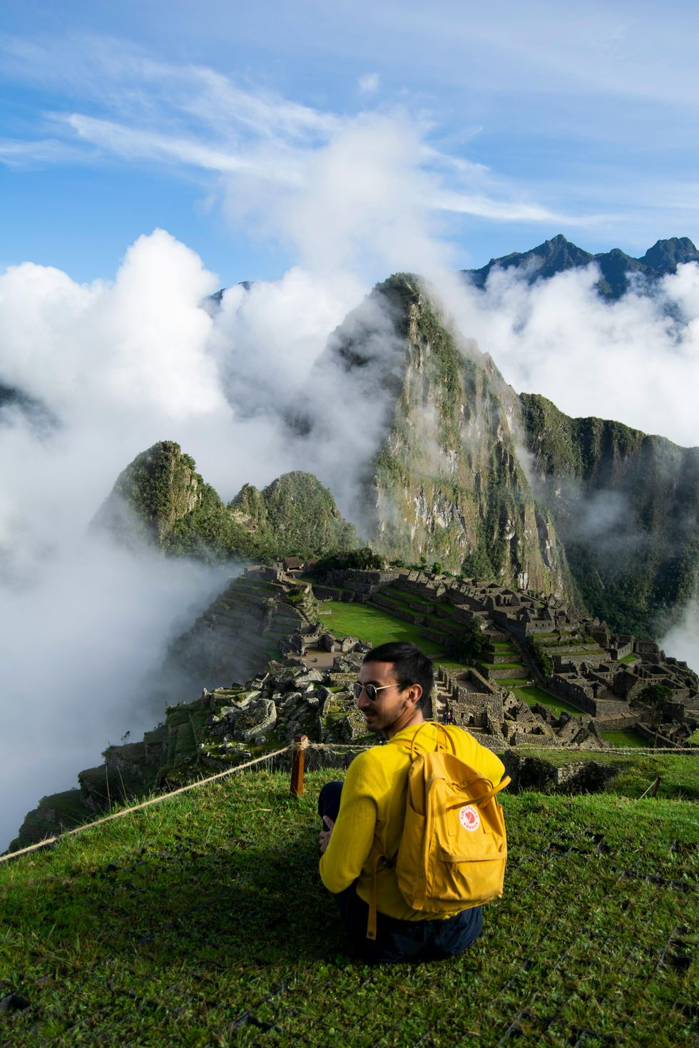 A tourist sits on a peak overlooking Machu Picchu.