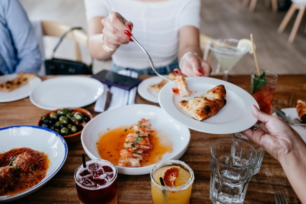 Someone passes food to another person at the table in a restaurant.