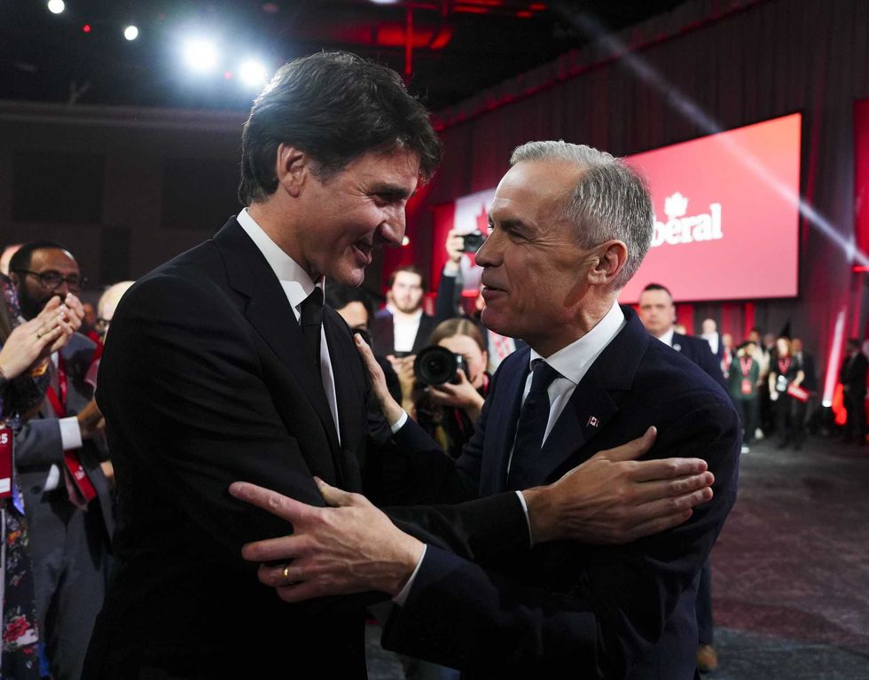 Mark Carney and Justin Trudeau speak and embrace at a Liberal convention.
