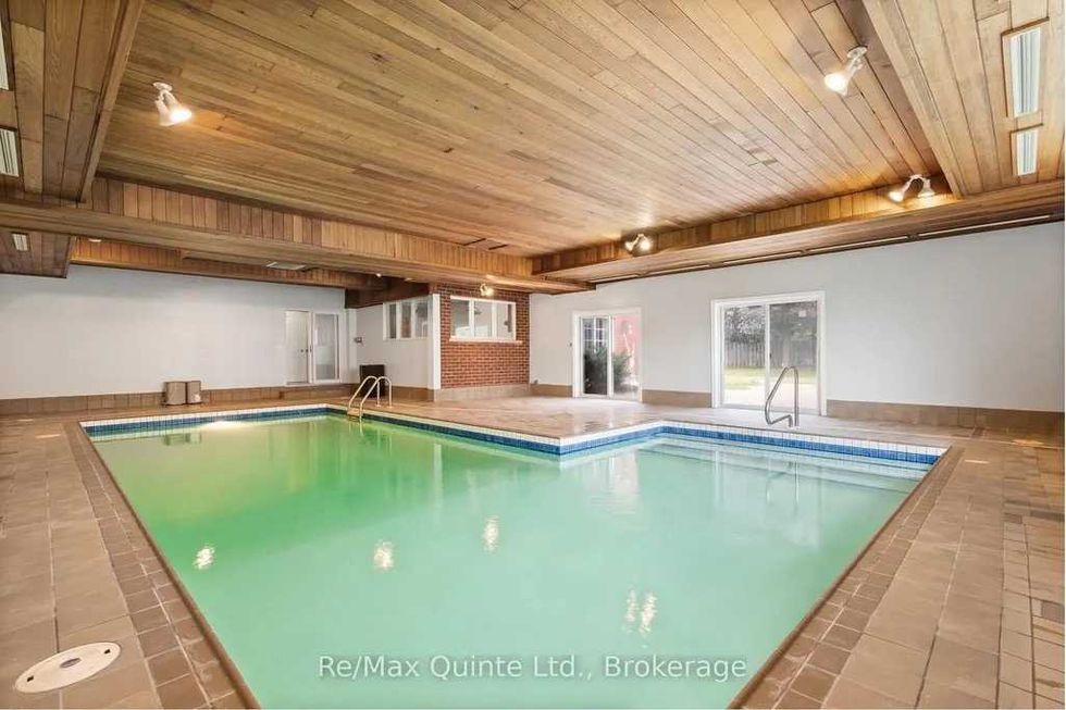 Indoor pool with wooden ceiling and soft lighting.