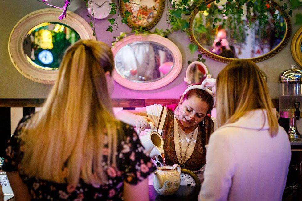 Woman wearing bunny ears pouring tea into a pot.