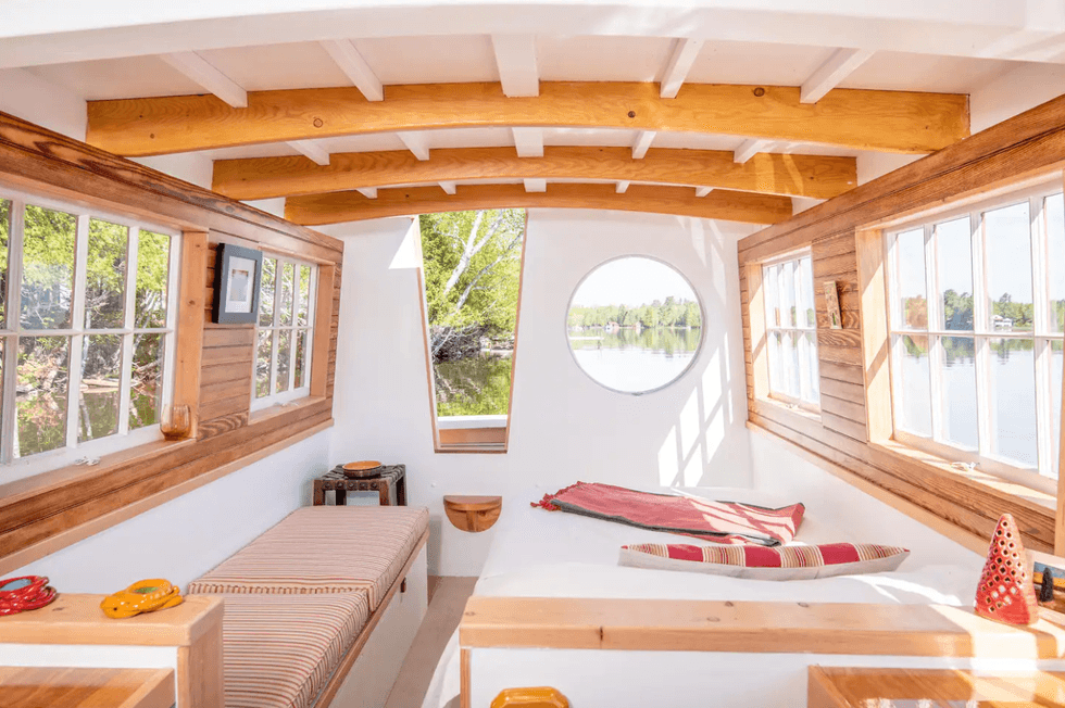 The interior of the floating Airbnb with large windows and a porthole.