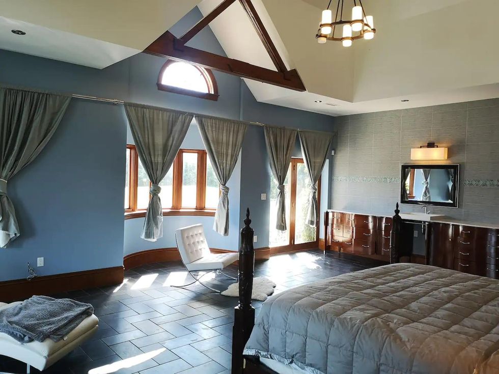 Master bedroom with modern finishes and high ceilings in country estate home.