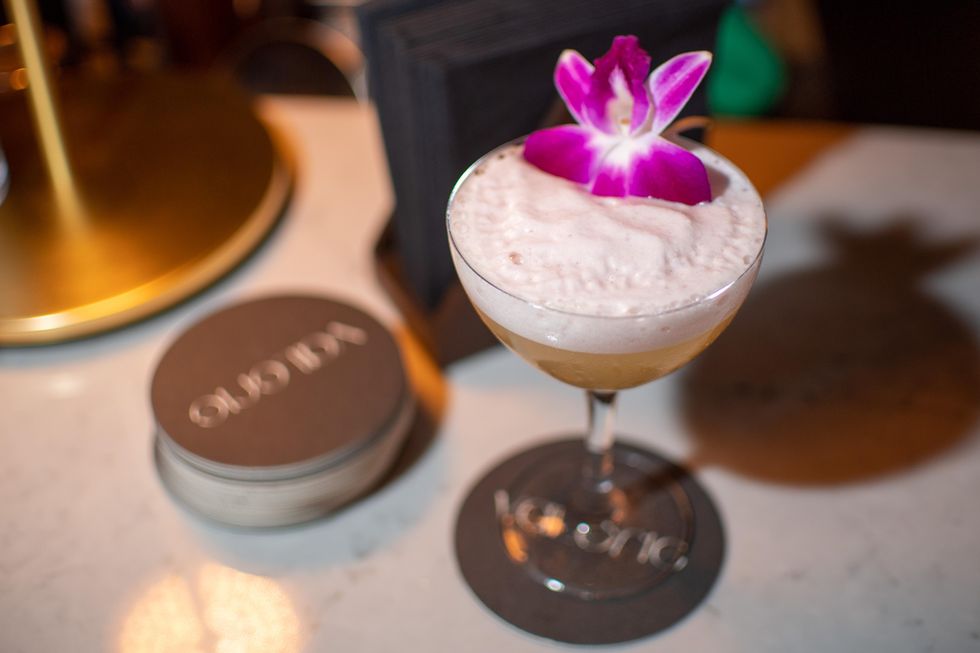 Cocktail with purple flower on top.