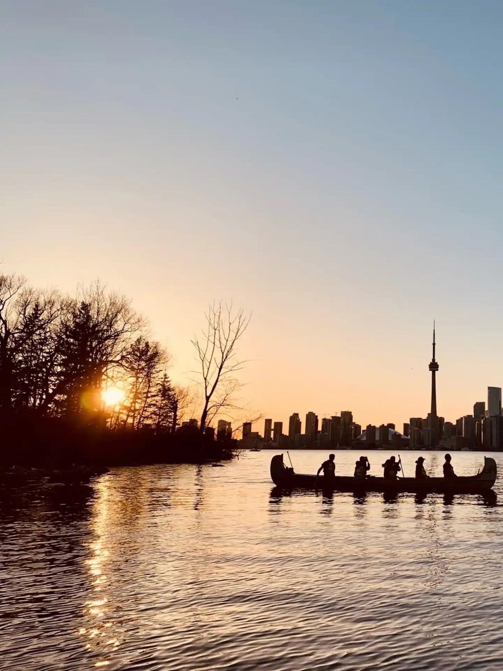 People in a canoe with the Toronto skyline in the background.