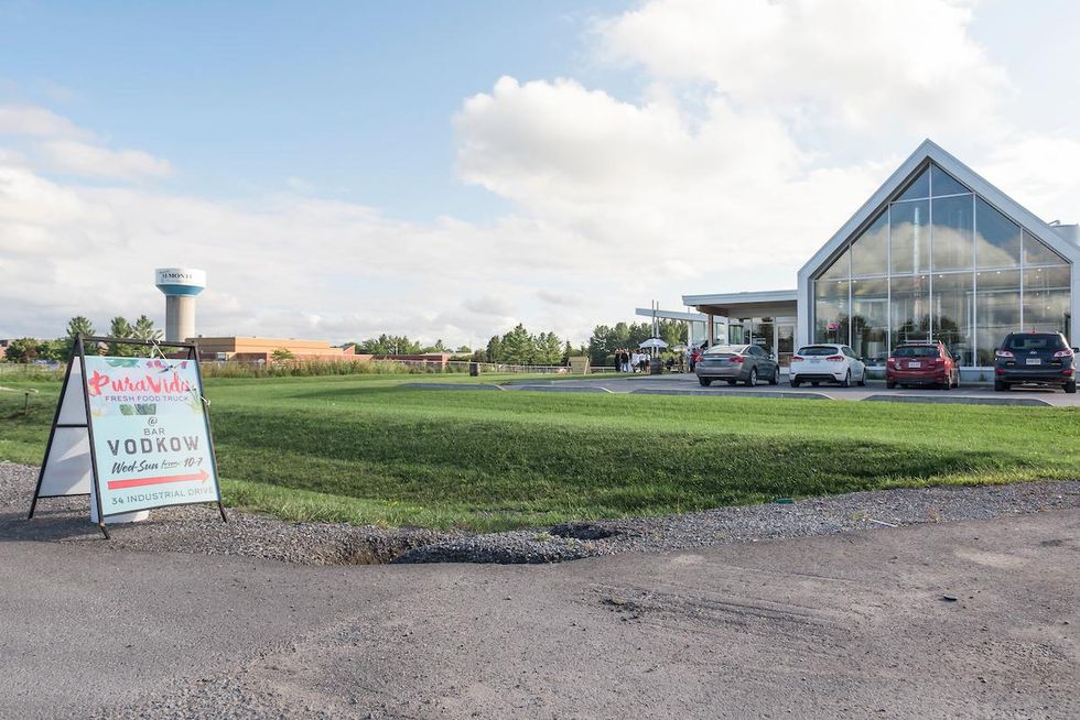 Dairy Distillery exterior with pitched roof and giant glass front by a spacious lawn.