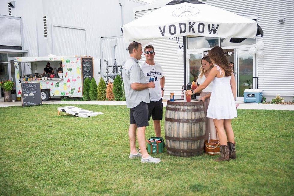 Friends having cocktails on a lawn patio by a food truck.