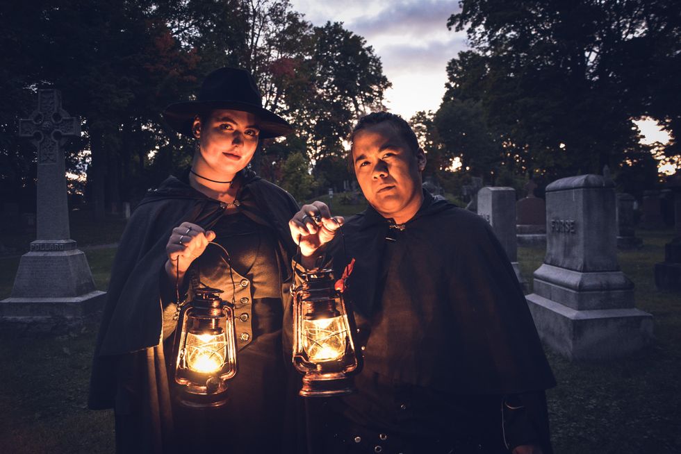 Haunted tour guides holding lanterns in Beechwood Cemetery.