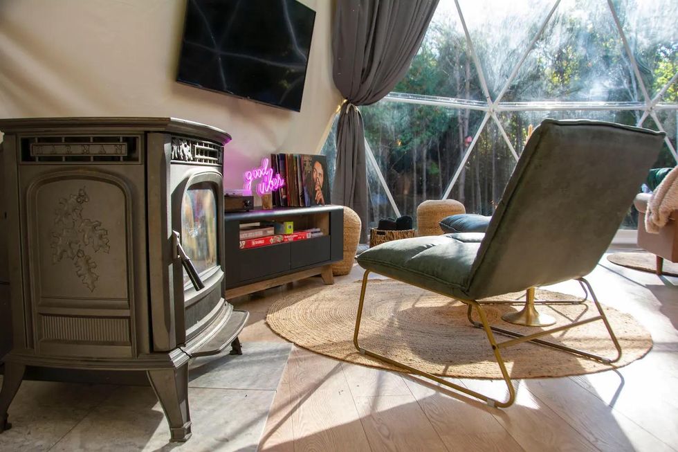 Pellet stove, chair and TV in a cozy glamping Airbnb rental.