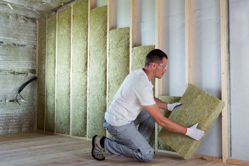 A worker installs insulation in a home.